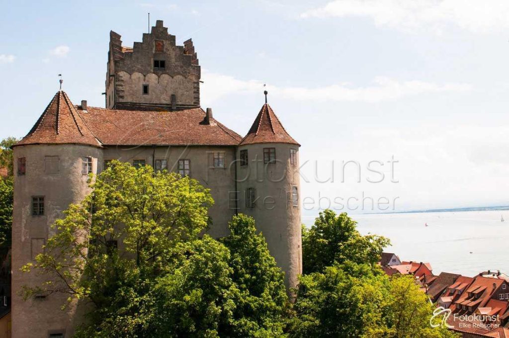 der mittelalterliche Bau der Burg Meersburg in der Stadt Meersburg mit Blick zum Bodensee und einigen B&auml;umen davor und einige H&auml;user der Stadtauf der rechten Seite