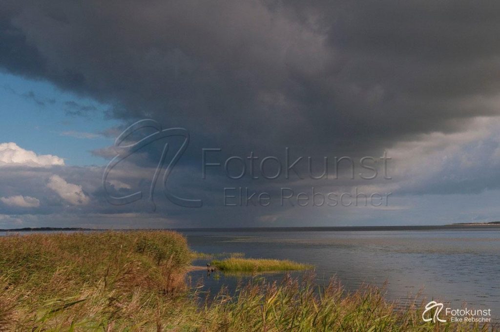 dunkel bedrohliche Wolken über den Salzwiesen und dem Meer der Nordseeinsel Amrum an der östlichen Seite der Insel mit Blick auf die Nordseeinsel Föhr